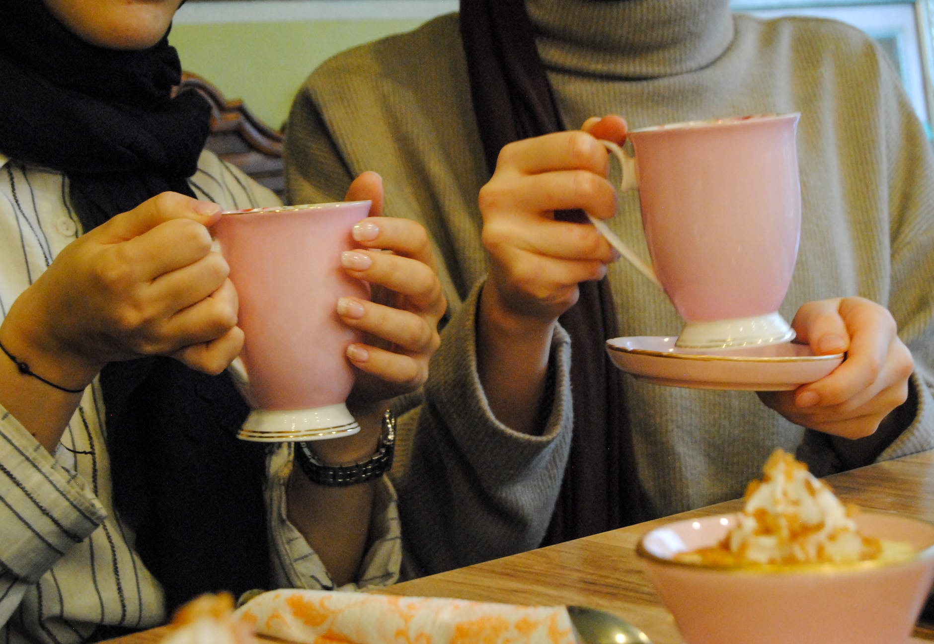 women holding coffee in pink cups